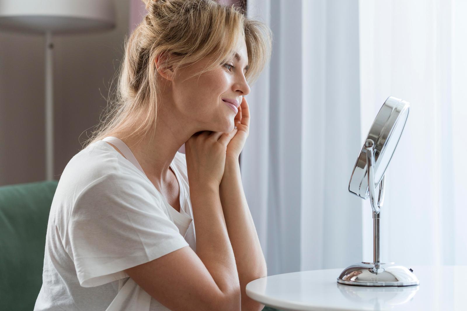 Femme prenant soin de son visage devant un miroir